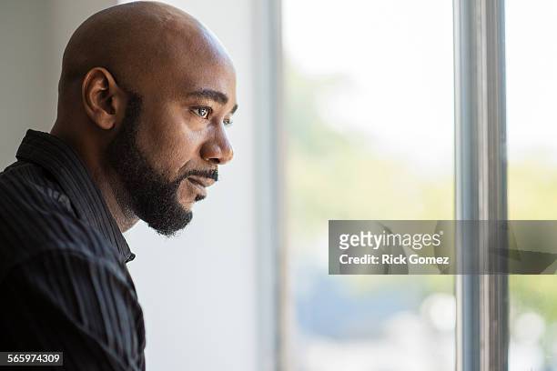 black man looking out window - black male profile stockfoto's en -beelden