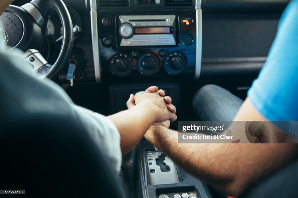 Caucasian couple holding hands in car