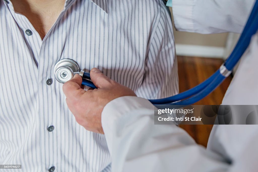 Caucasian doctor listening to heartbeat of patient
