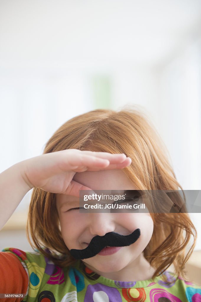 Caucasian girl wearing fake mustache