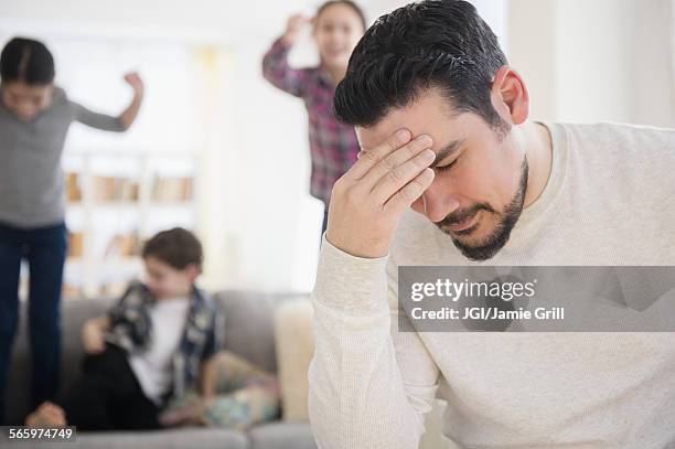 stressed caucasian father with shouting children in living room - social projects address needs of struggling families stockfoto's en -beelden