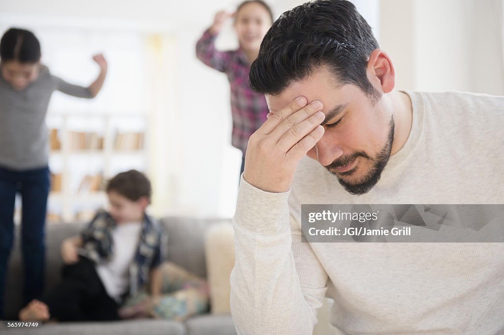 Stressed Caucasian father with shouting children in living room