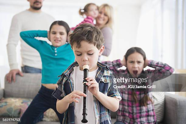 caucasian family covering ears with boy playing recorder - recorder musical instrument stock pictures, royalty-free photos & images