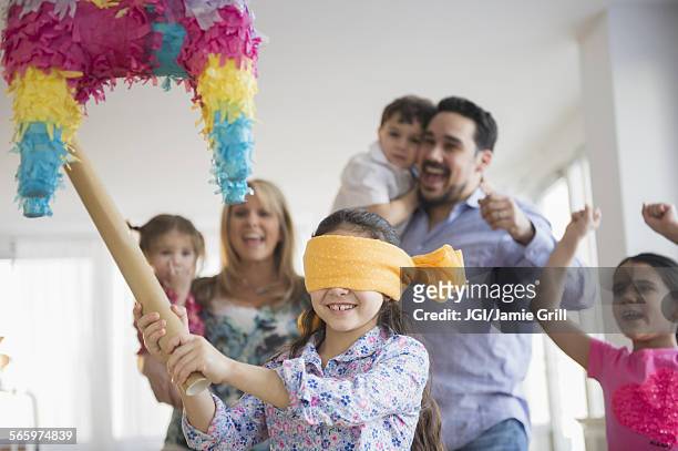 caucasian girl hitting pinata at birthday party - piñata fotografías e imágenes de stock