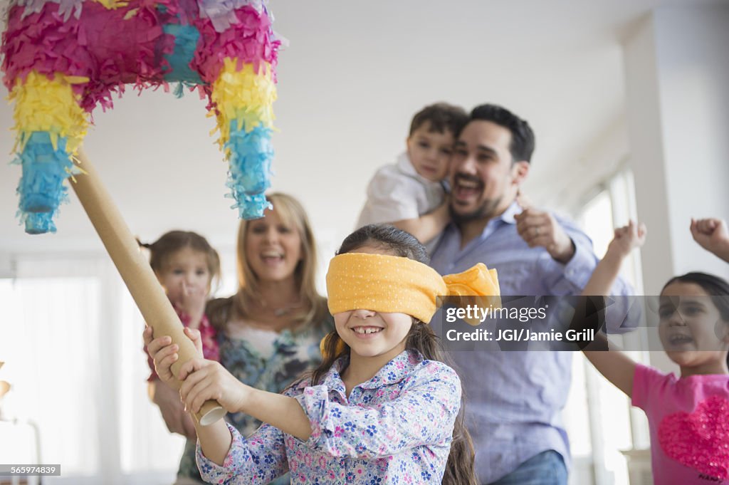 Caucasian girl hitting pinata at birthday party