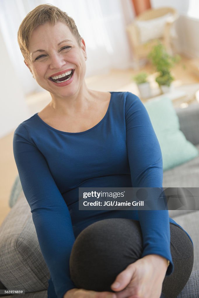 Laughing Caucasian woman sitting on sofa