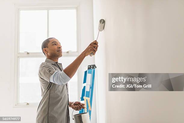 black man painting wall of home - wand streichen stock-fotos und bilder