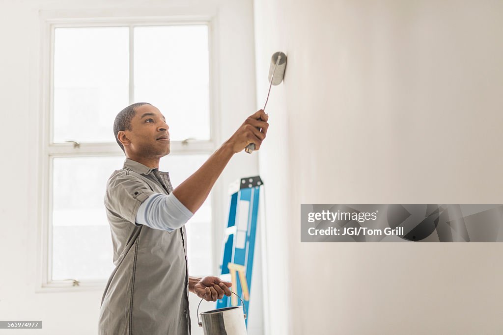Black man painting wall of home