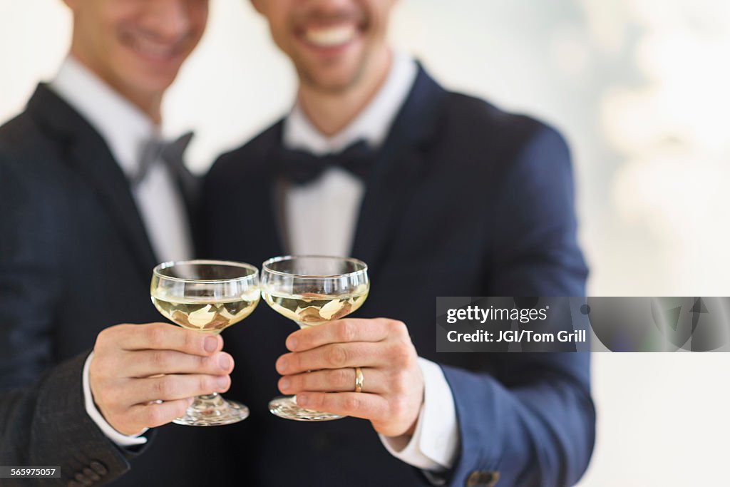 Caucasian gay grooms toasting with champagne at wedding