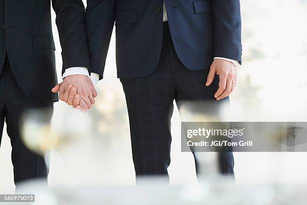 caucasian gay grooms holding hands at wedding - gay marriage stockfoto's en -beelden