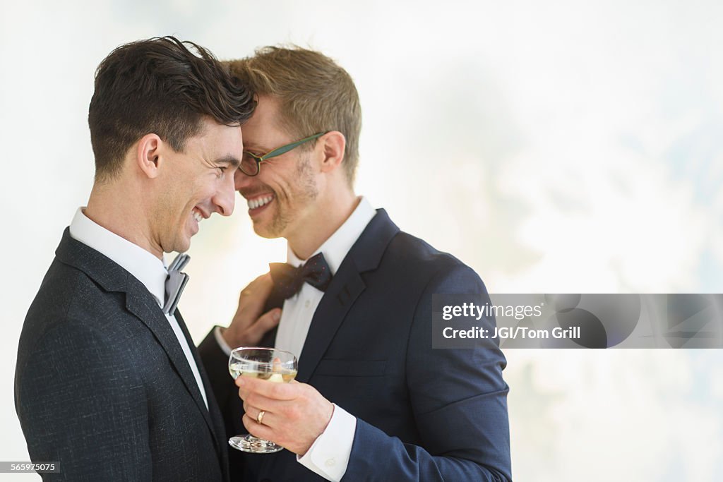 Caucasian gay grooms hugging at wedding