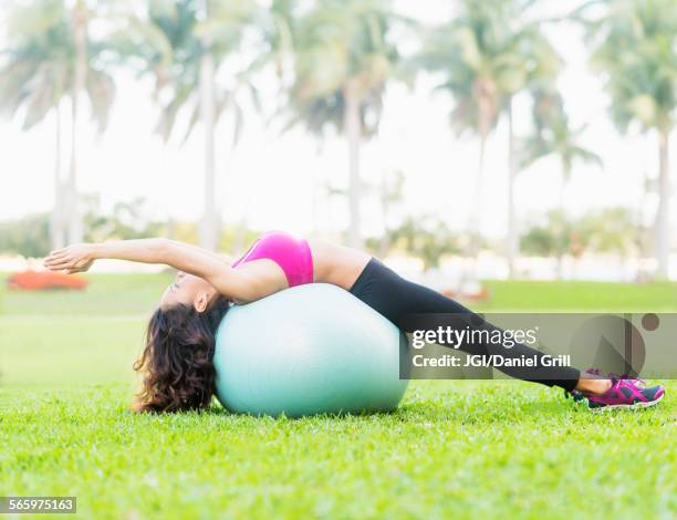 chinese woman stretching on fitness ball in park - yoga ball fotografías e imágenes de stock