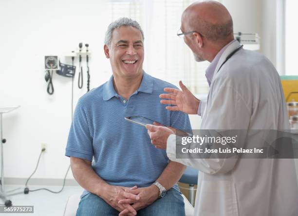 doctor using digital tablet and talking to patient in office - hombre revision fotografías e imágenes de stock