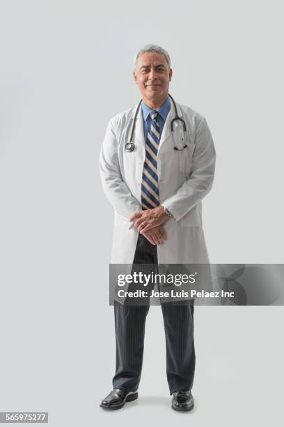 smiling hispanic doctor wearing stethoscope - man standing against grey background foto e immagini stock