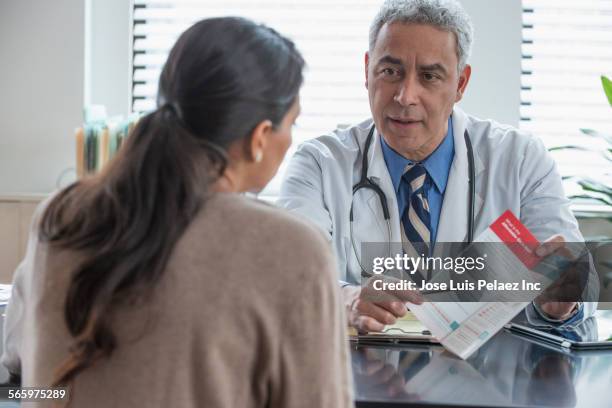 hispanic doctor explaining pamphlet to client in office - doctor publication stock pictures, royalty-free photos & images