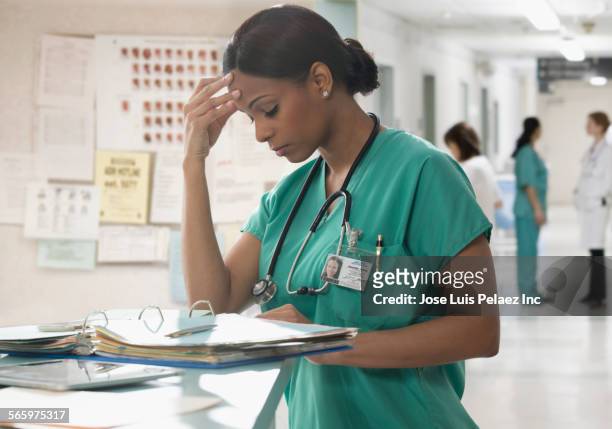 anxious mixed race nurse doing paperwork in hospital - angry black woman stock pictures, royalty-free photos & images
