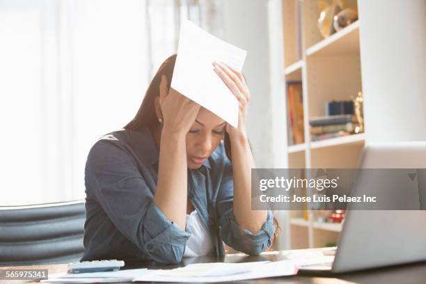 anxious mixed race woman paying bills on laptop - preocupado fotografías e imágenes de stock