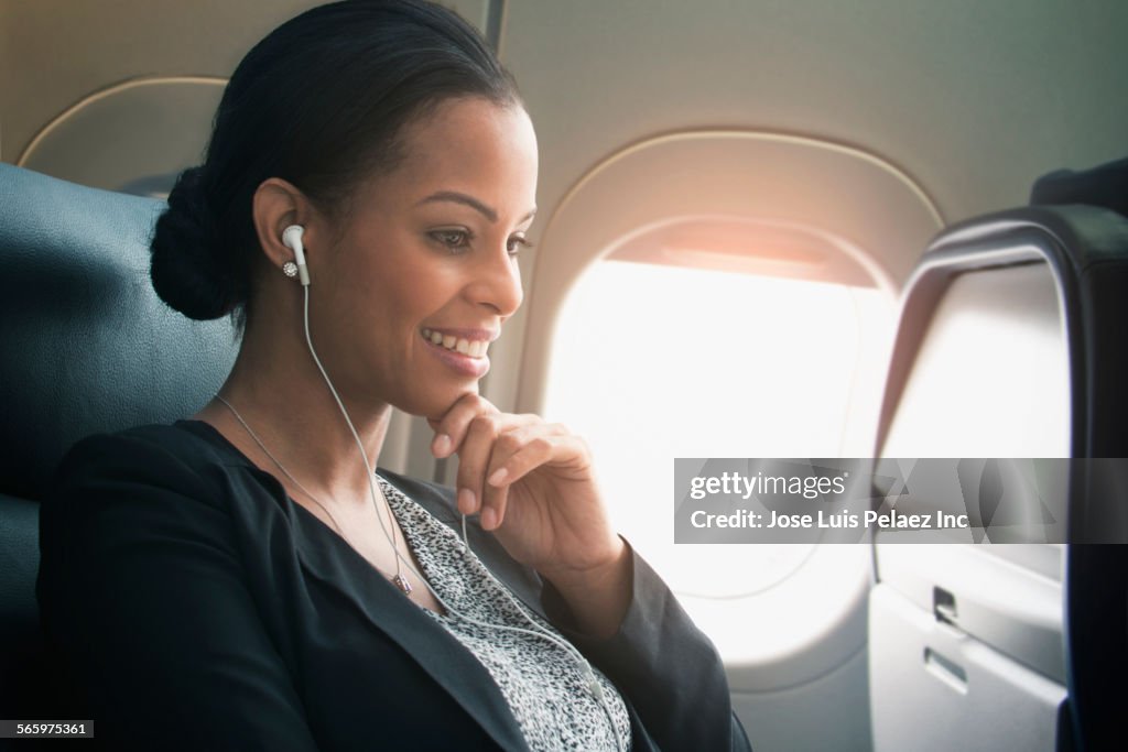 Businesswoman listening to earbuds on airplane