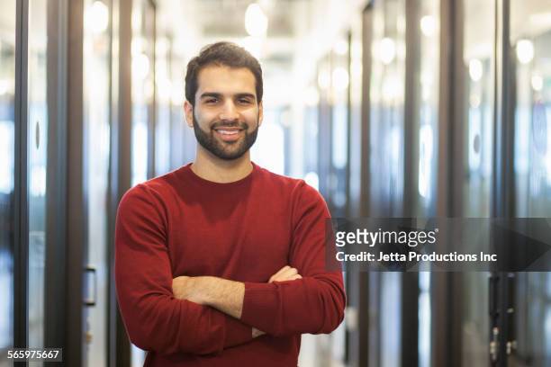mixed race businessman smiling in office hallway - ethnies du moyen orient photos et images de collection