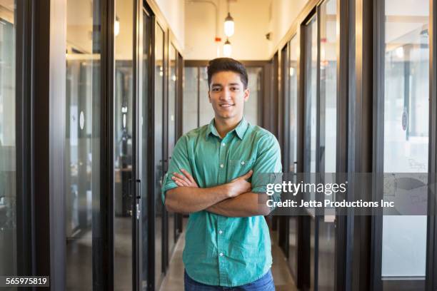 indian businessman smiling in office hallway - waist up stock pictures, royalty-free photos & images