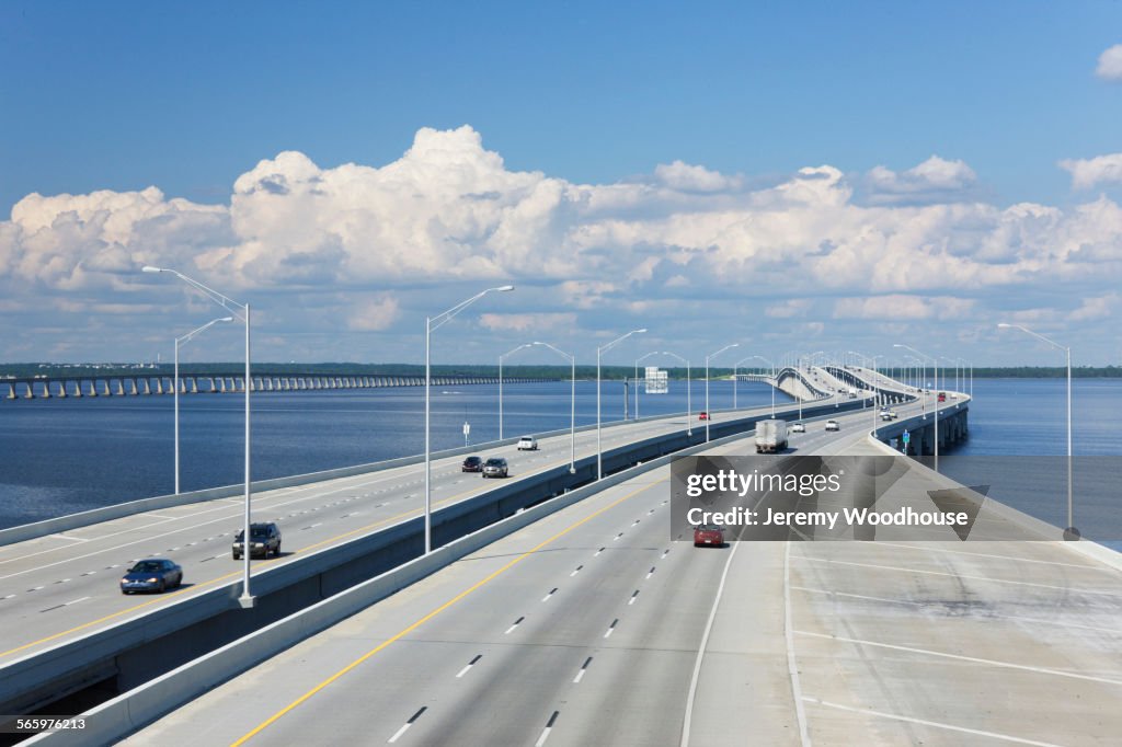 Aerial view of highway bridge across bay under blue sky