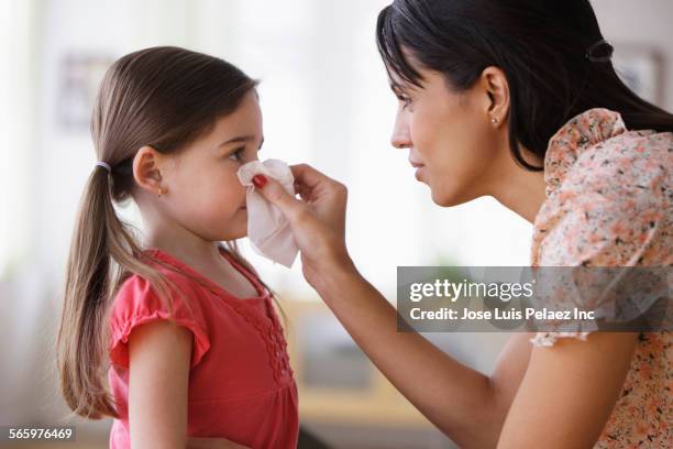 mother wiping nose of daughter with tissue - allergia foto e immagini stock