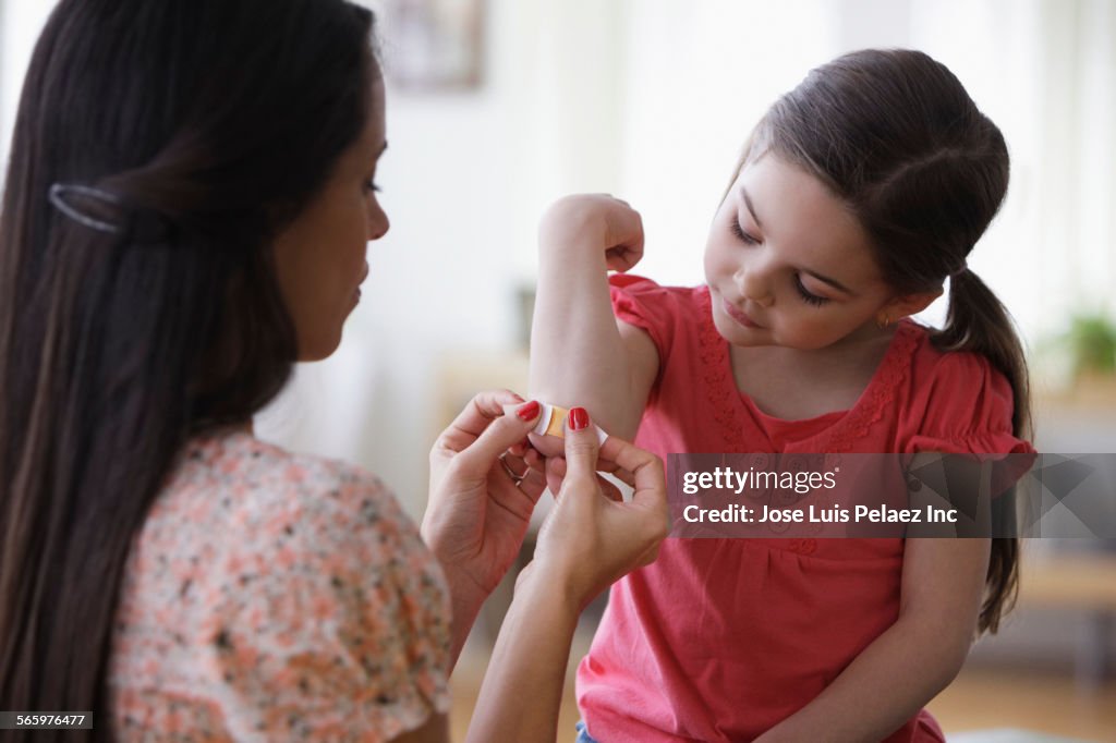 Mother bandaging elbow of daughter