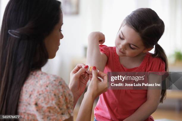 mother bandaging elbow of daughter - wunder stock-fotos und bilder