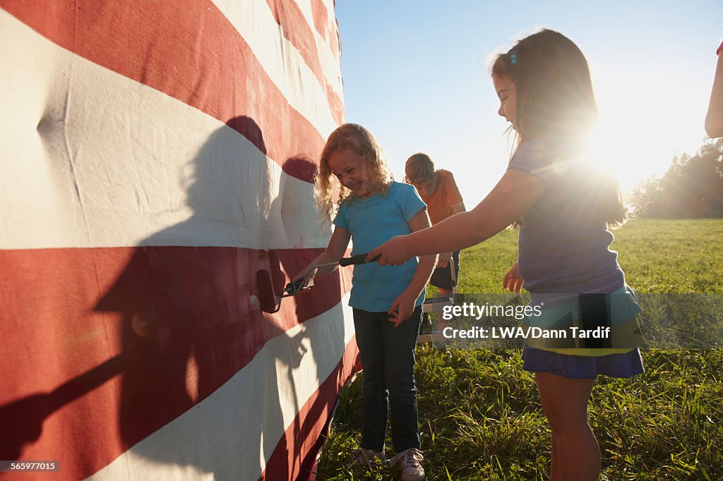 Caucasian children painting American flag in field