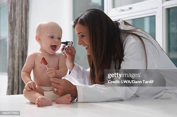 caucasian doctor examining ear of baby - pediatra foto e immagini stock