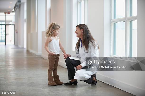 caucasian doctor and girl talking in hallway - child standing talking stockfoto's en -beelden