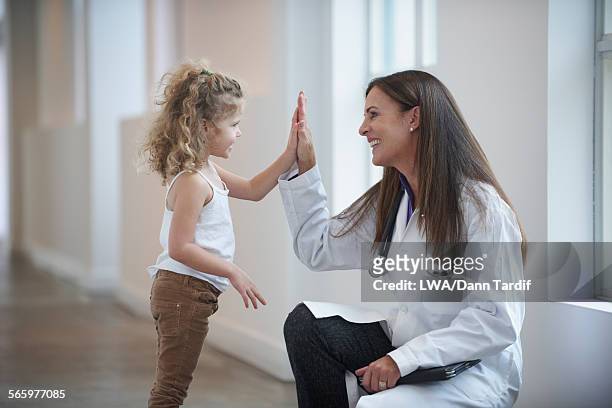 caucasian doctor and girl high-fiving in hallway - young doctor stockfoto's en -beelden