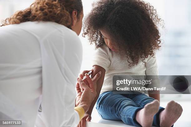 doctor vaccinating girl in office - jamaican girl stock pictures, royalty-free photos & images