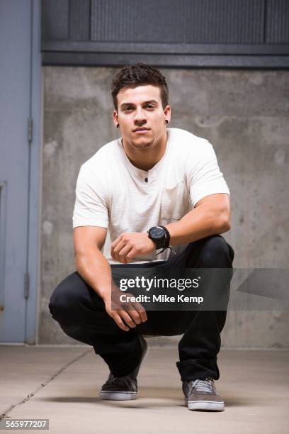 pacific islander man crouching on floor - knielen stockfoto's en -beelden