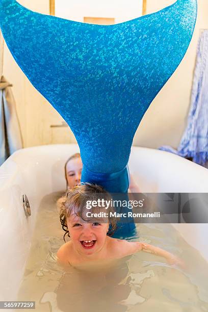 caucasian children playing with mermaid tail in bath - house flipper fotografías e imágenes de stock