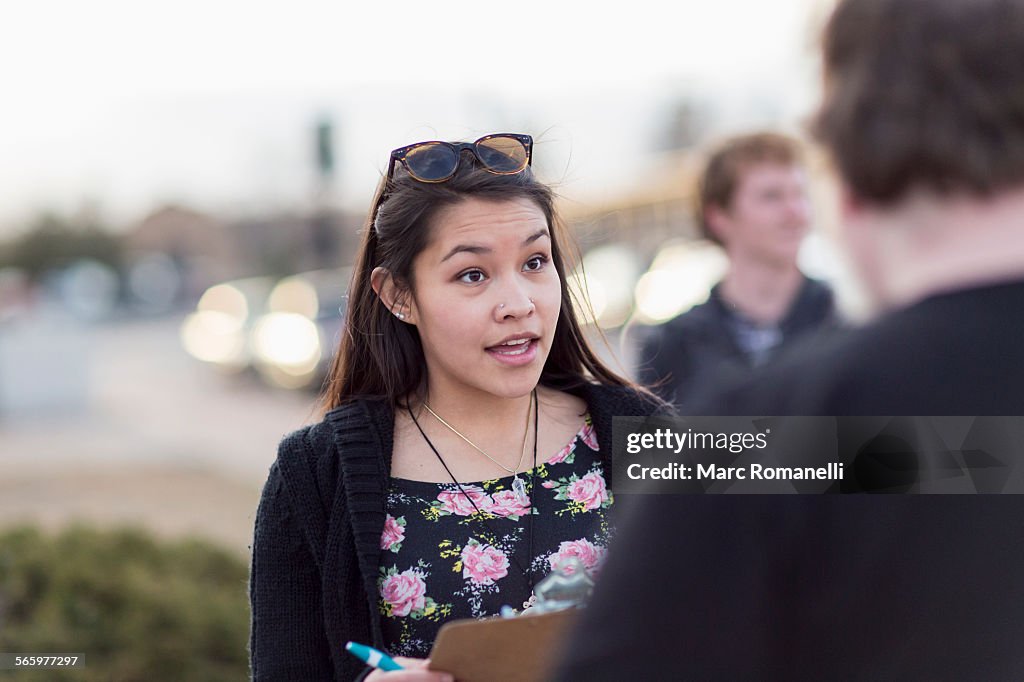 Canvasser with clipboard talking to man