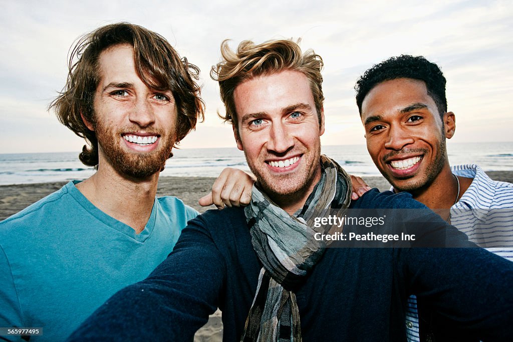 Smiling men taking selfie on beach