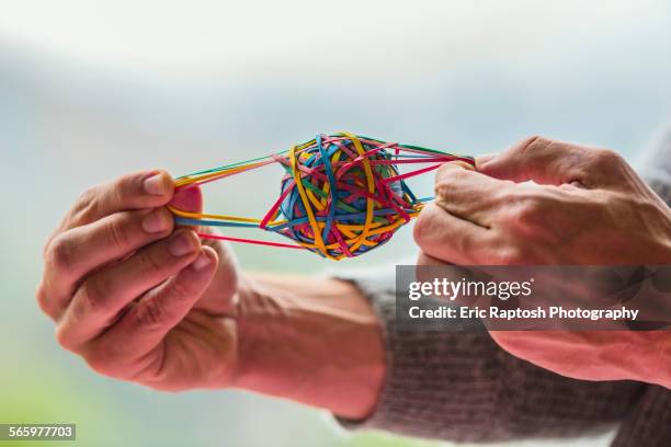 close up of caucasian man pulling rubber band ball - gummiband stock-fotos und bilder