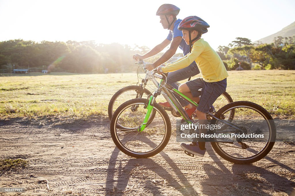 Caucasian father and son riding bicycles on dirt path