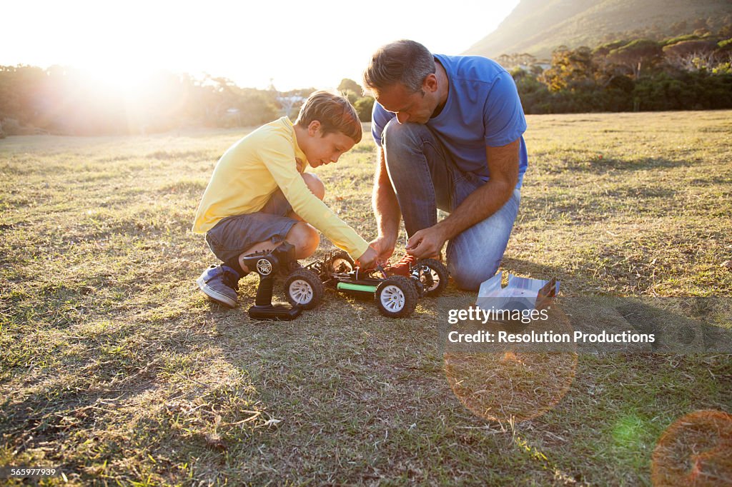 Caucasian father and son playing with remote control cars in field