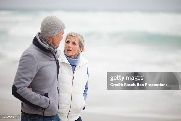 caucasian couple walking on beach - romantic couple walking winter beach stock-fotos und bilder