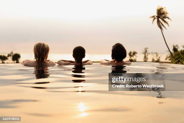 women admiring scenic view in infinity pool - infinity pool stockfoto's en -beelden