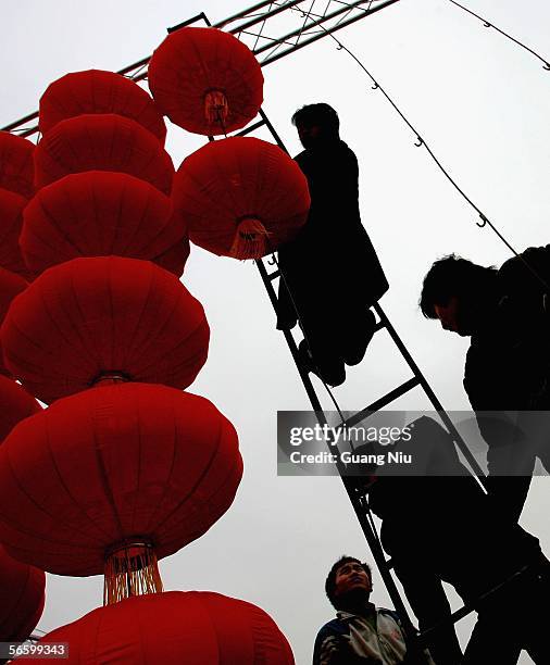 Workers hang up red lanterns in preparation for Chinese New Year at a park on January 16, 2006 in Beijing, China.The red lantern, one of the main...