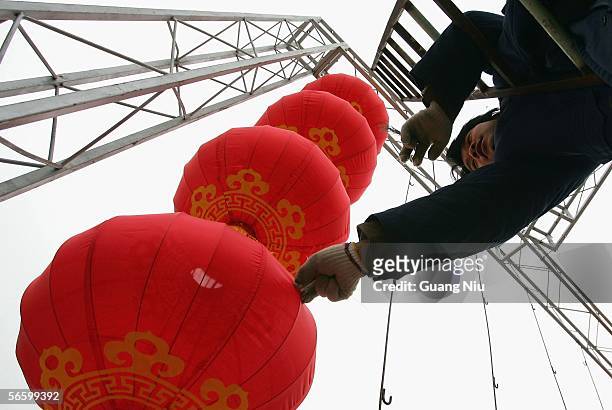 Workers hang up red lanterns in preparation for Chinese New Year at a park on January 16, 2006 in Beijing, China.The red lantern, one of the main...