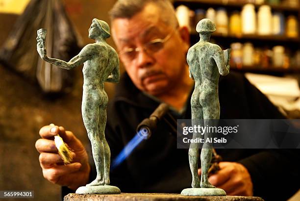 Joaquin Quintero uses a brush and blow torch to apply a chemical oxidation which creates the verdigris green color to the SAG statuette cast in...