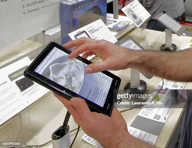 Kindle Fire in the hands of a customer. Best Buy customers browsing/handling new tablet computer devices like the Kindle Fire and Barnes and Noble...