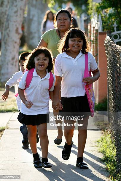 Dana Hernendez and sister Melani Gomez followed by their 5yearold brother Holberto Hernandez and mother Ana Gomez, sprint towards school on the...