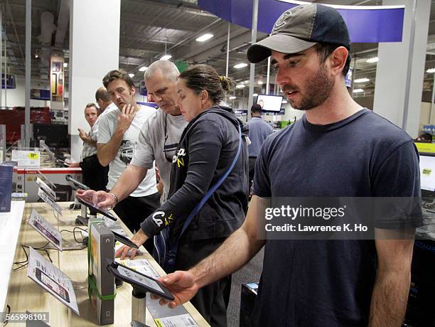 Best Buy customers like Tim Perkins browsing/handling new tablet computer devices like the Kindle Fire and Barnes and Noble Nook on Nov. 21, 2011.