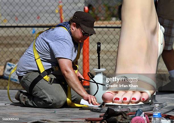 Michael Benevenia polishes foot of "Forever Marilyn". Statue of iconic blonde Marilyn Monroe stands at her new home in downtown Palm Springs....