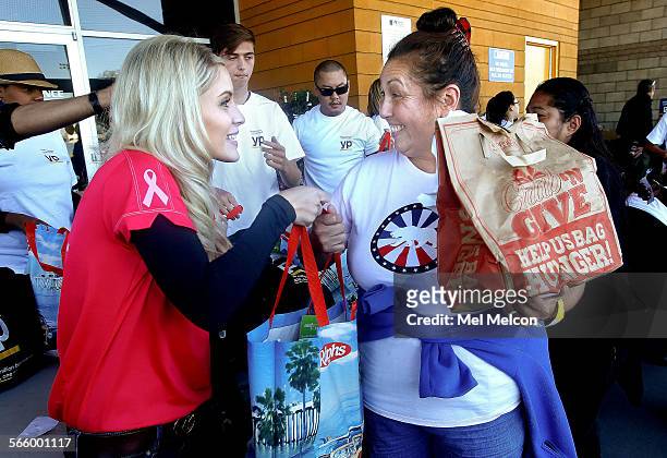 Volunteer Tara McGee, left, hands a bag filled with a frozen turkey to Denise Garcia during the ninth annual Healthy Family Update and Turkey...